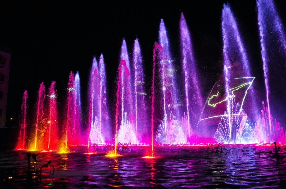 una grande fontana d'acqua con luci rosa e viola