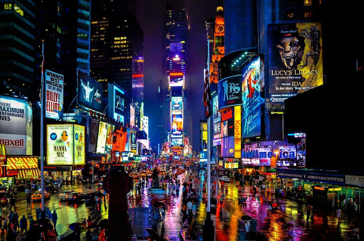 una strada cittadina trafficata di notte con insegne al neon