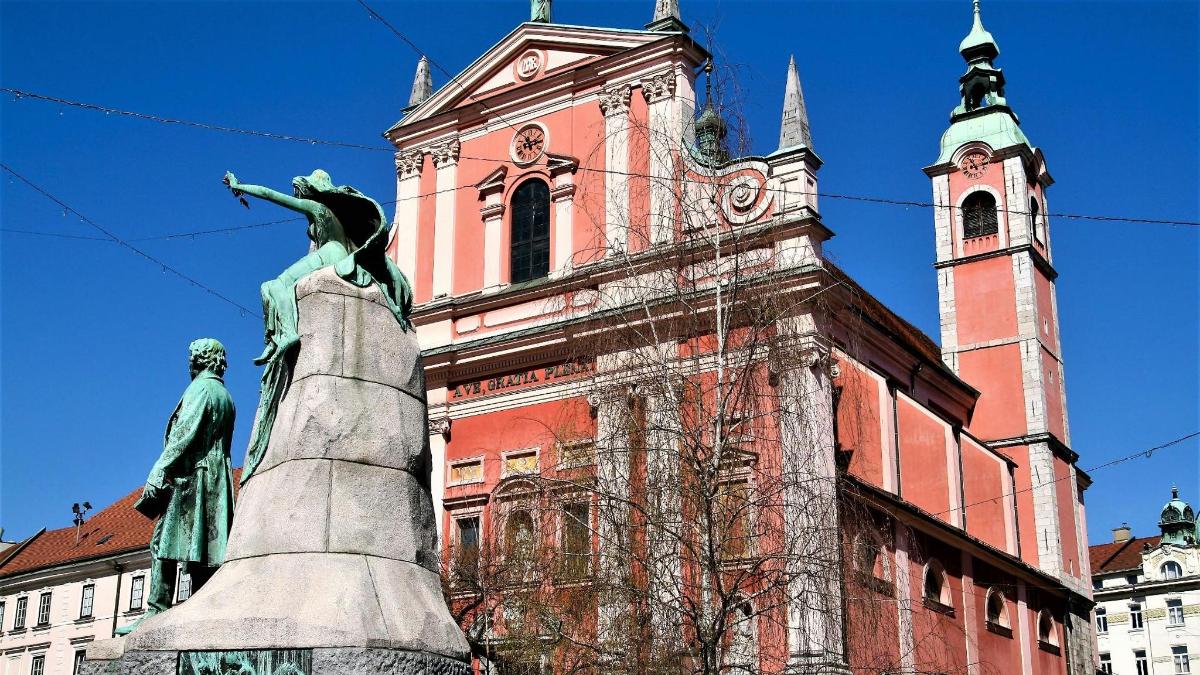 uma estátua em frente a um prédio com uma torre de relógio