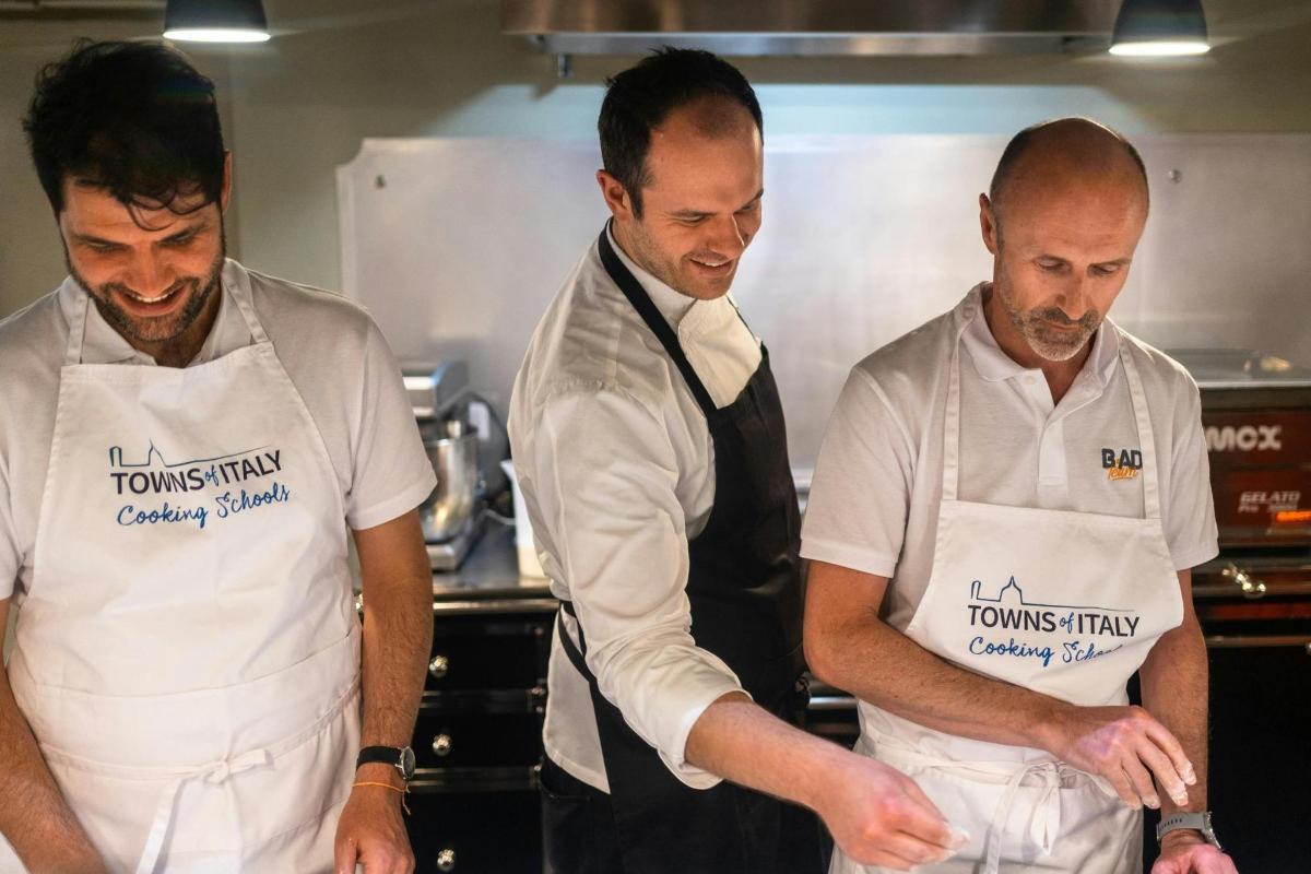 Un grupo de tres hombres en una cocina preparando comida.