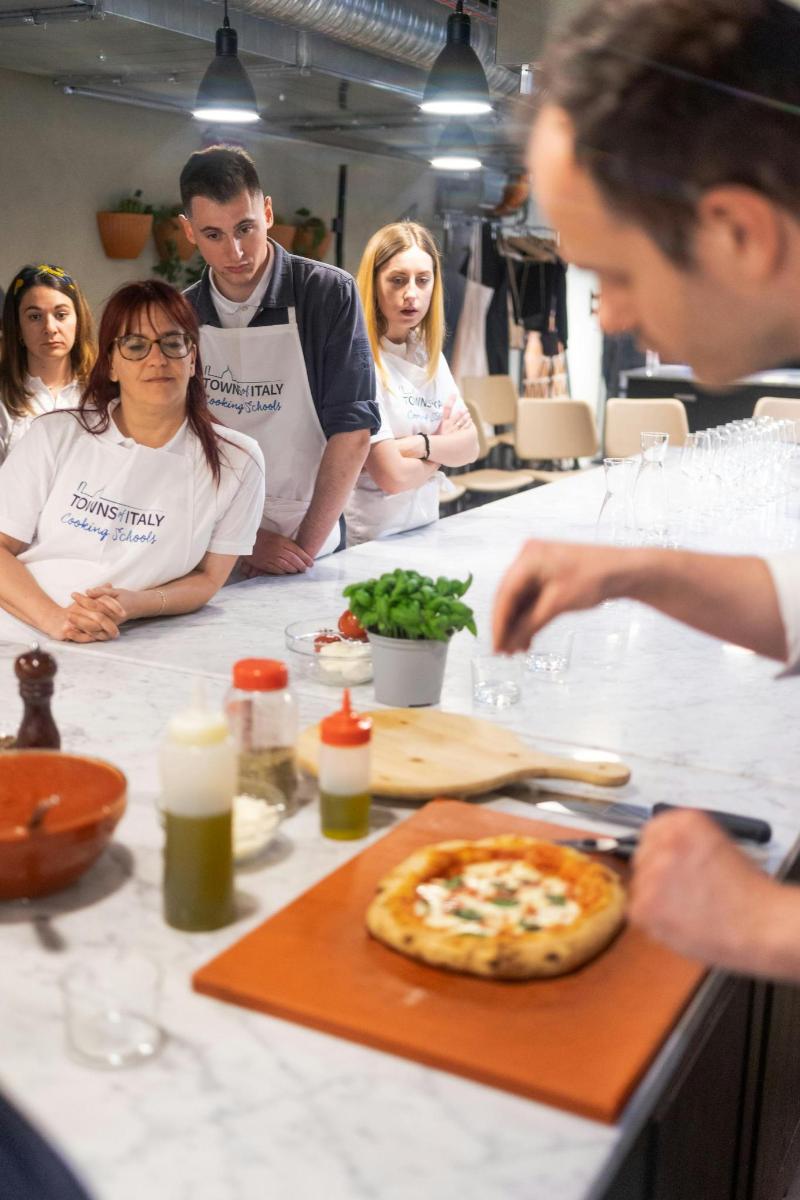 Un grupo de personas de pie alrededor de una mesa con una pizza.