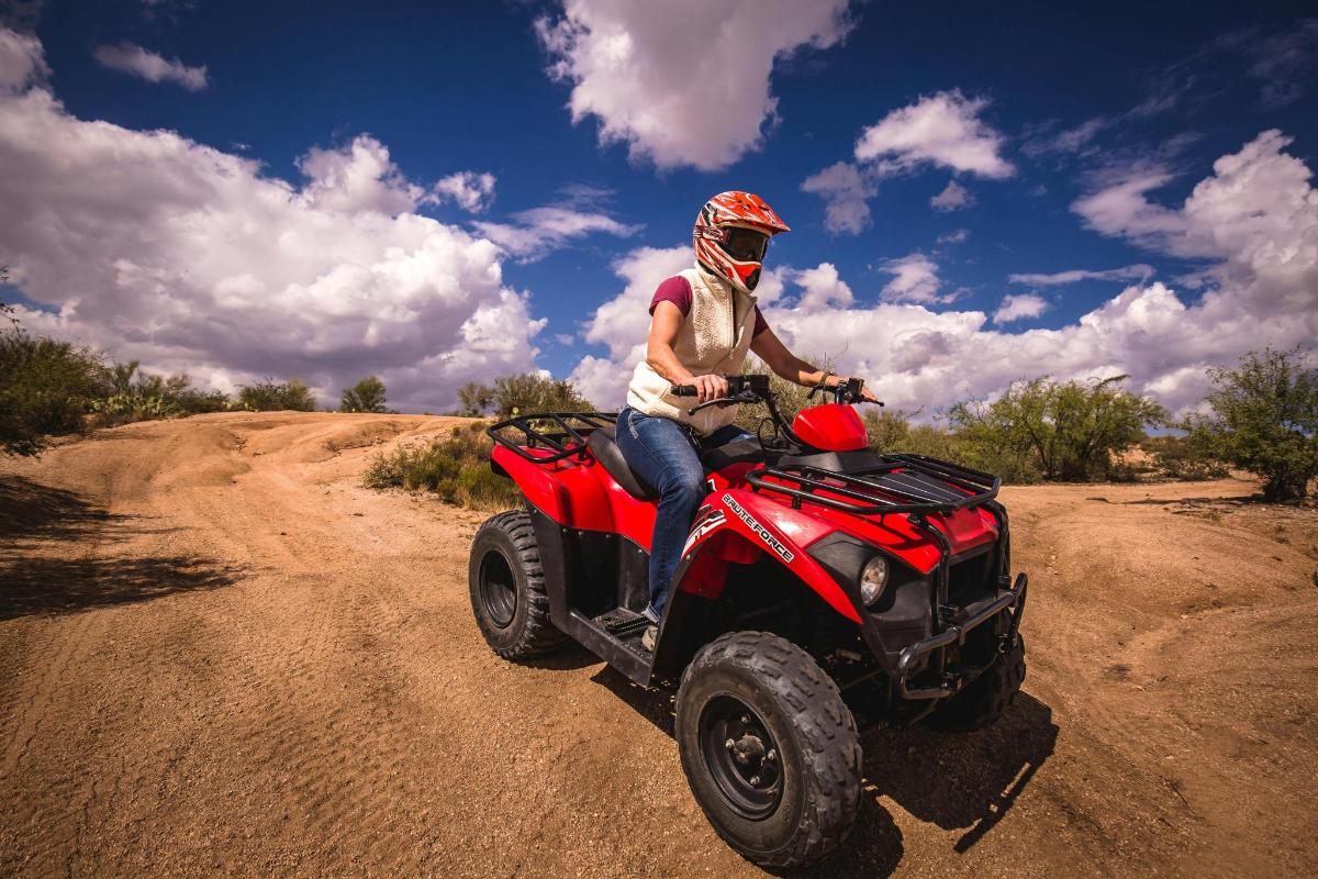 a man riding a red atv on a dirt road