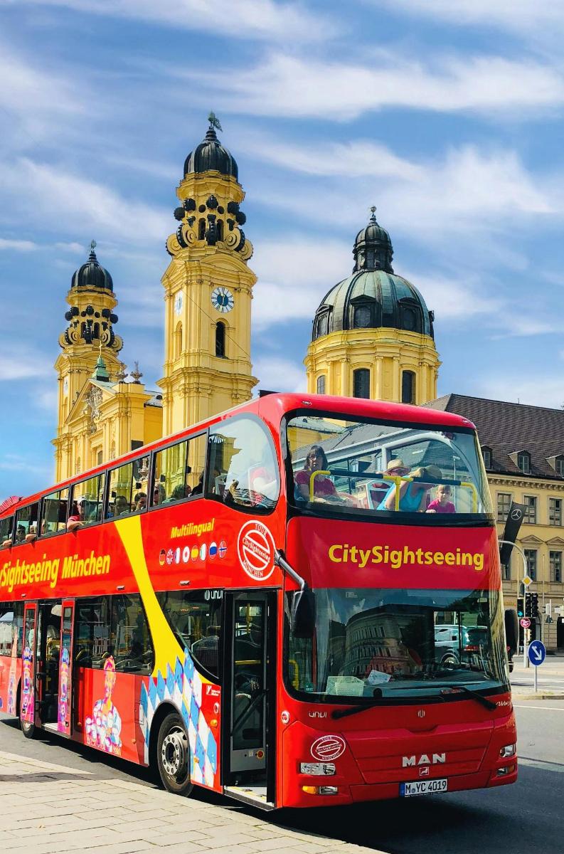 raudonas dviaukštis autobusas, pastatytas priešais pastatą