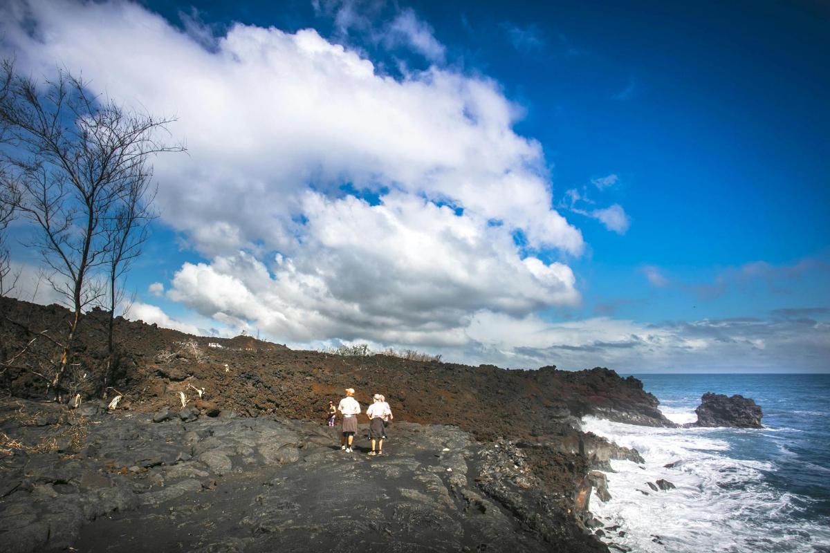 two people walking on a rocky beach near the ocean