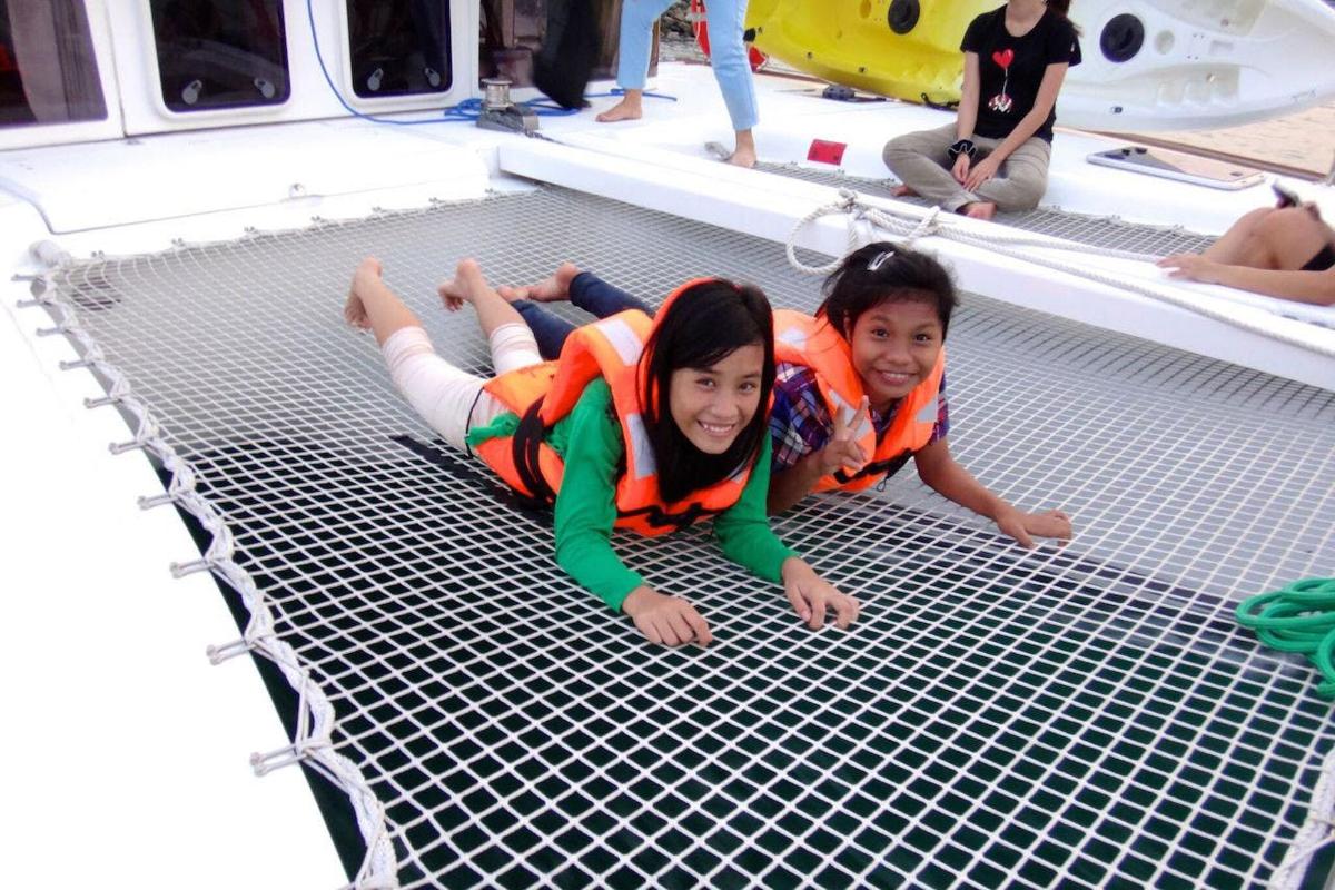Dos chicas están tendidas en una red en un barco.
