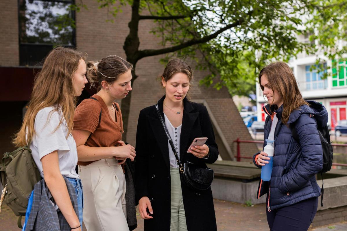 quattro donne in piedi che guardano un cellulare