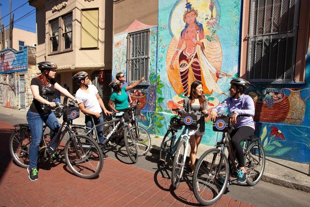 un grup de persones anant en bicicleta davant d'un mural