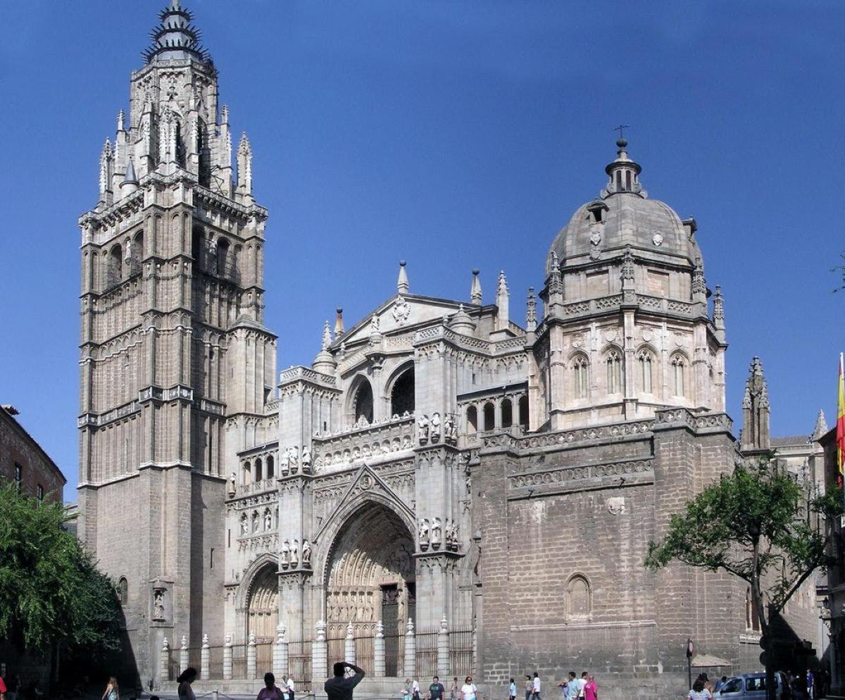 Una antigua catedral con dos torres y gente parada frente a ella.