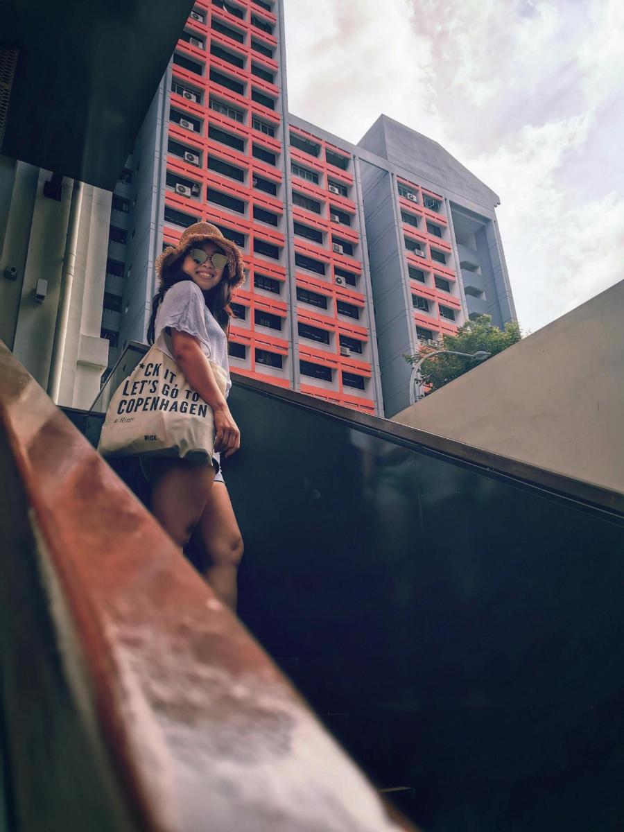 a woman standing on top of a fence in front of a building