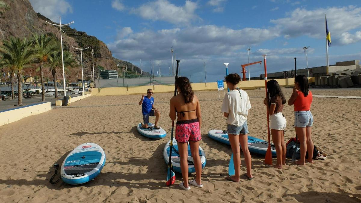 isang grupo ng mga tao na nakatayo sa isang beach na may mga surfboard