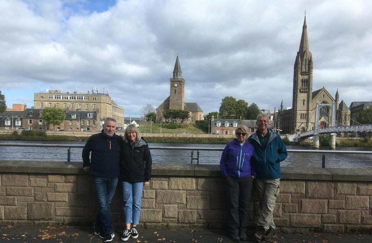a group of people standing on a wall near a river