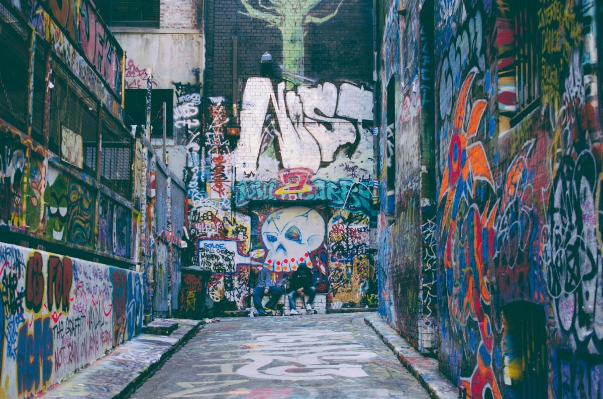 lorong yang dilitupi grafiti dengan seseorang berjalan menyusurinya