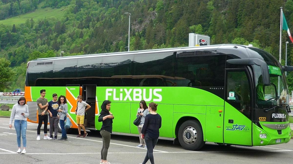 Un grupo de personas de pie frente a un autobús verde.