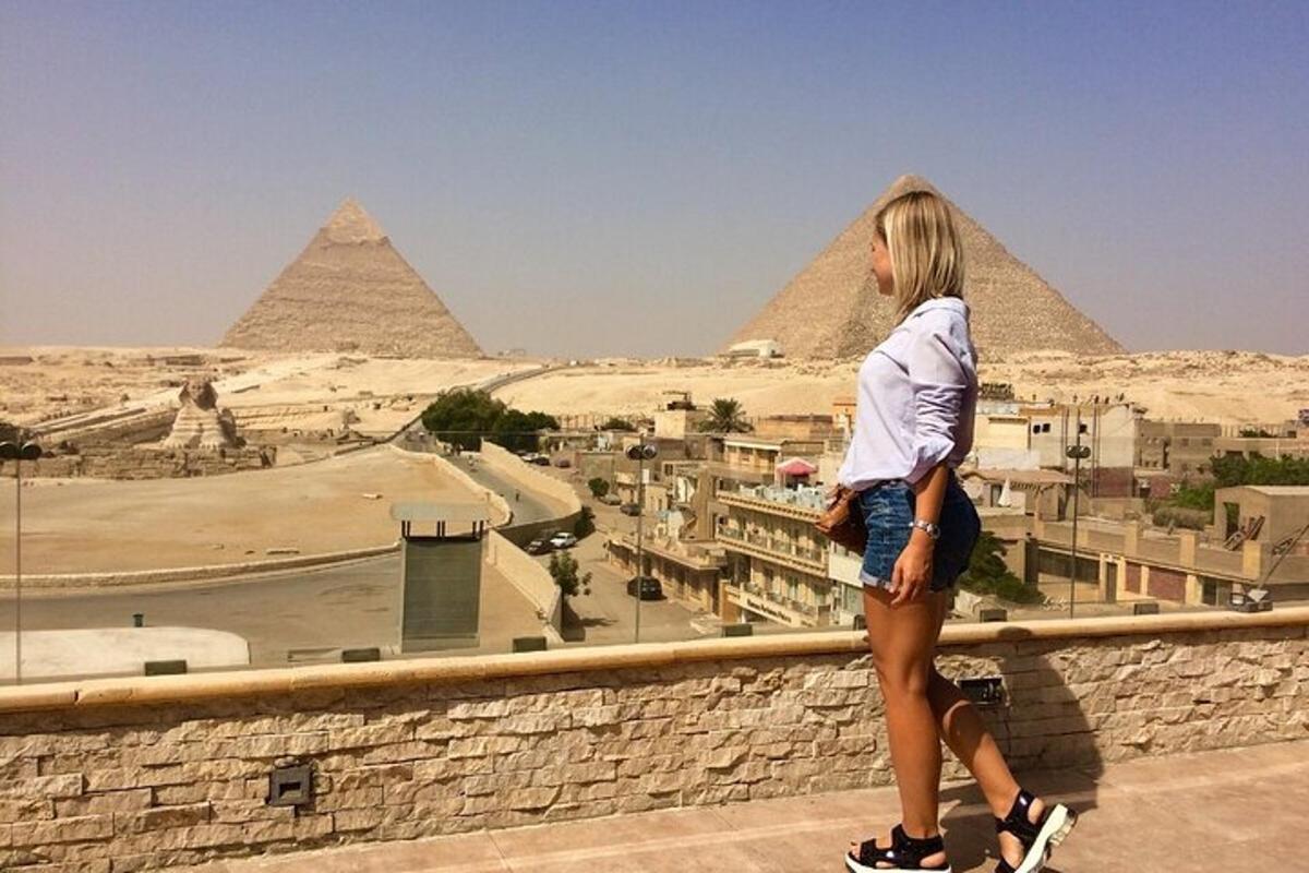 isang babaeng nakatayo sa dingding na nakatingin sa mga piramide