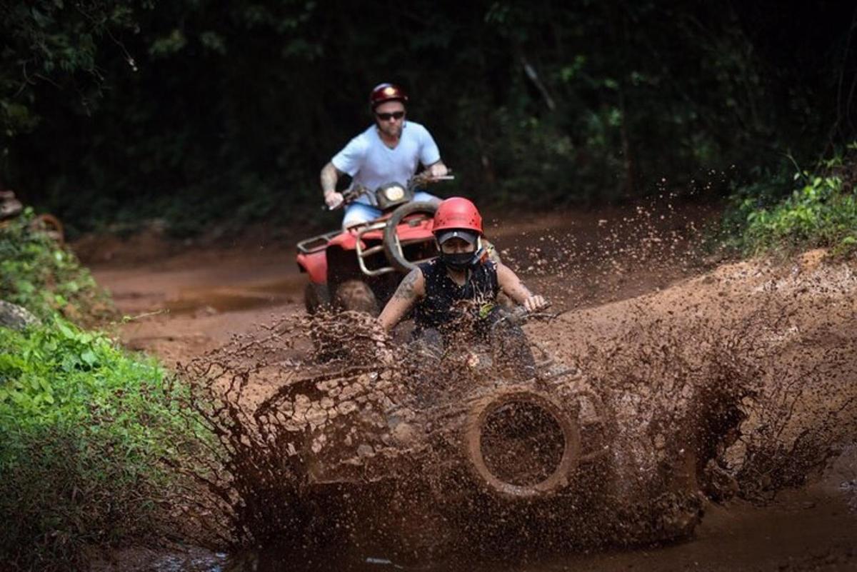 a man riding a quad bike through a muddy trail