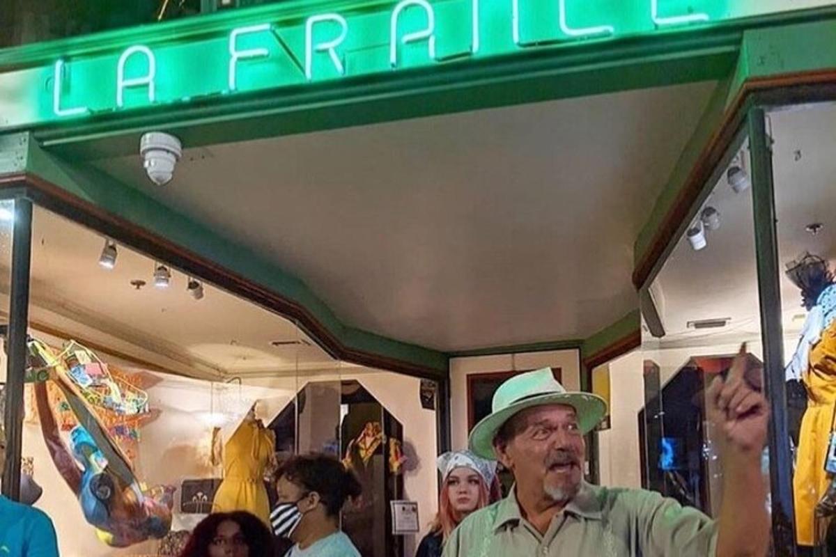 un uomo che indossa un cappello in piedi davanti a un negozio