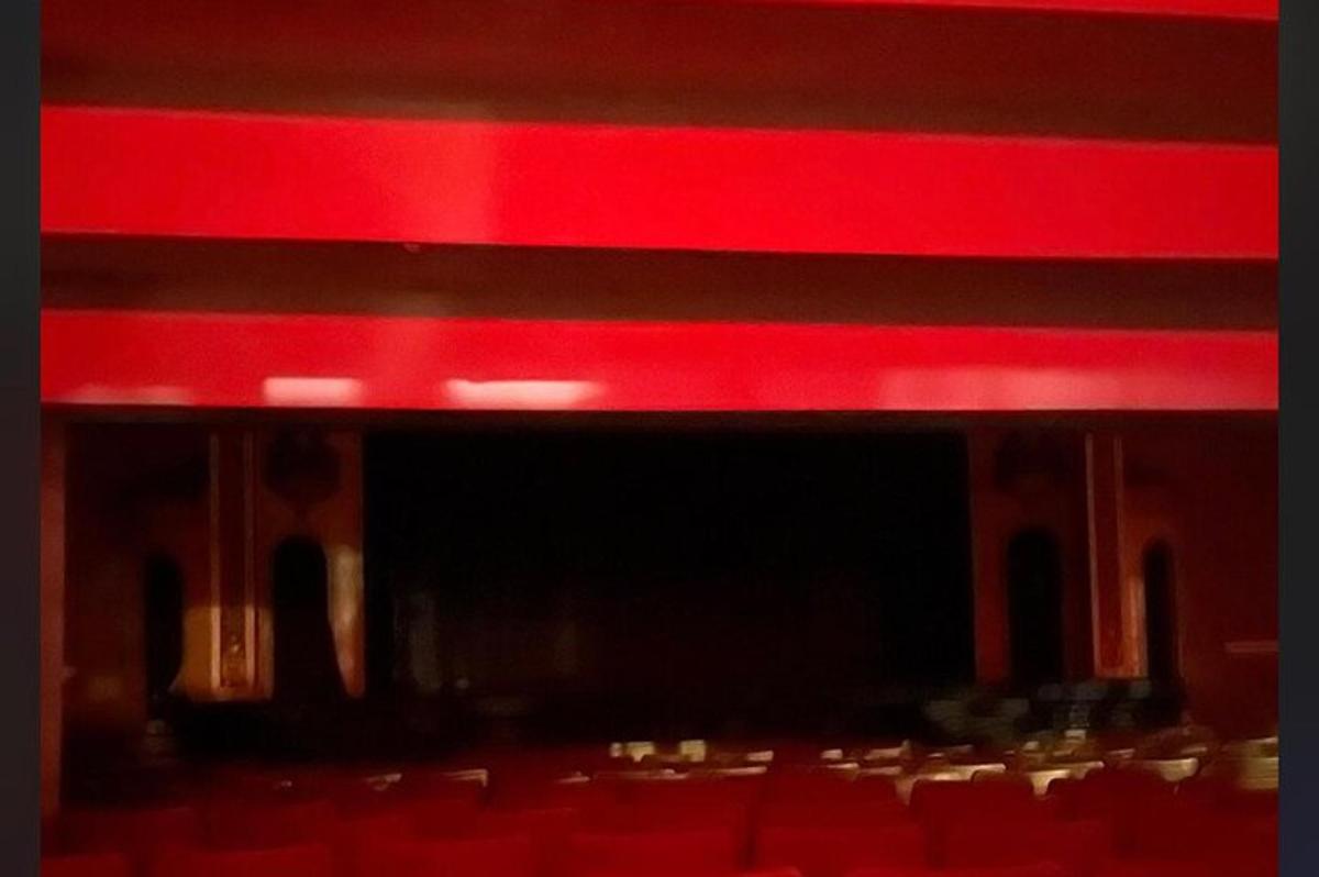 um palco vermelho com um grupo de cadeiras em um teatro