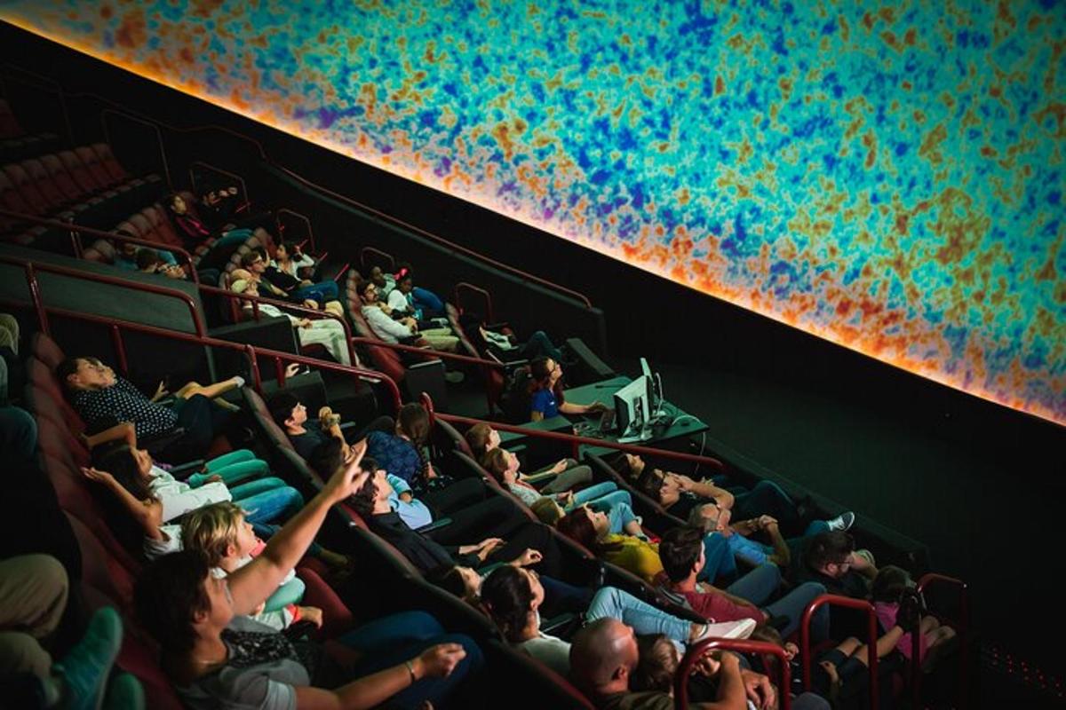 a crowd of people sitting in an auditorium with their hands up