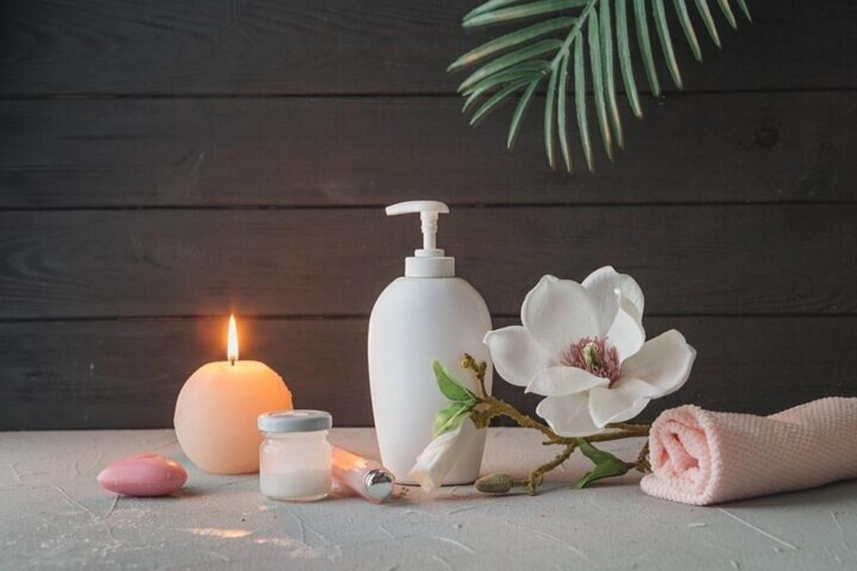 uma garrafa branca de sabonete, uma vela e flores