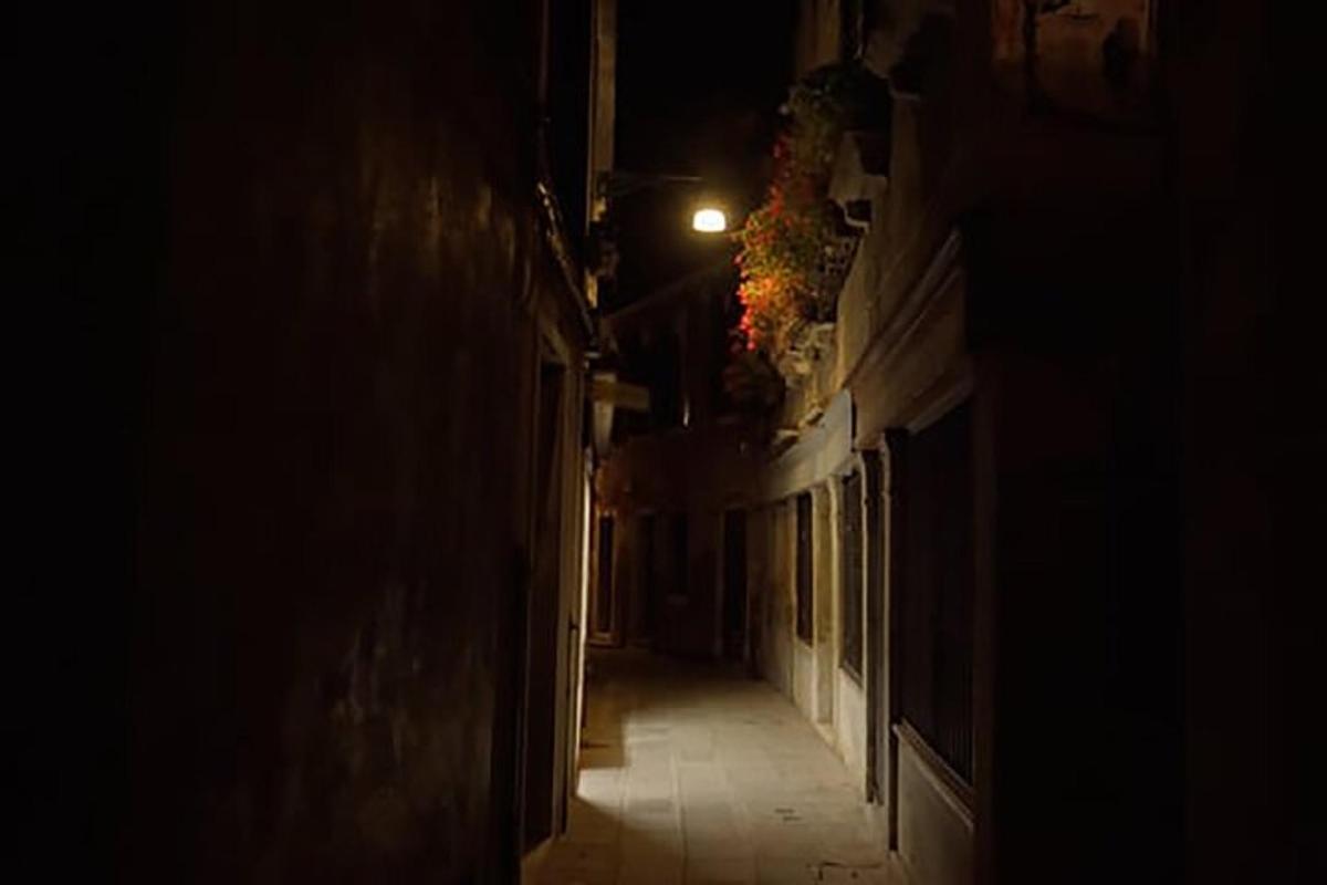 um beco escuro com uma luz na lateral de um prédio