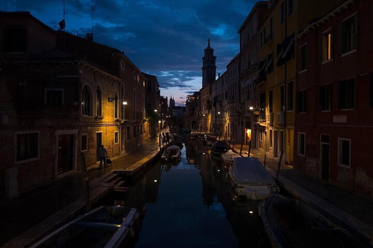uma rua da cidade à noite com barcos em um canal