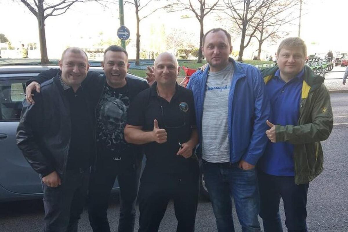 un grup de bărbați care stau în fața unei mașini