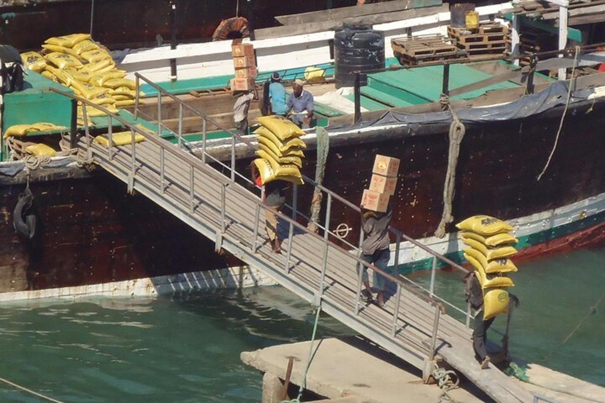 um grupo de pessoas em pé em uma doca ao lado de um barco