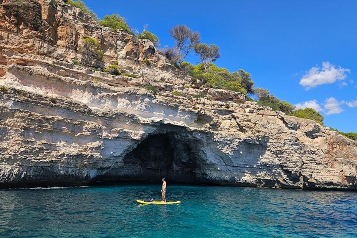 Un hombre parado en un kayak en una cueva en el agua.
