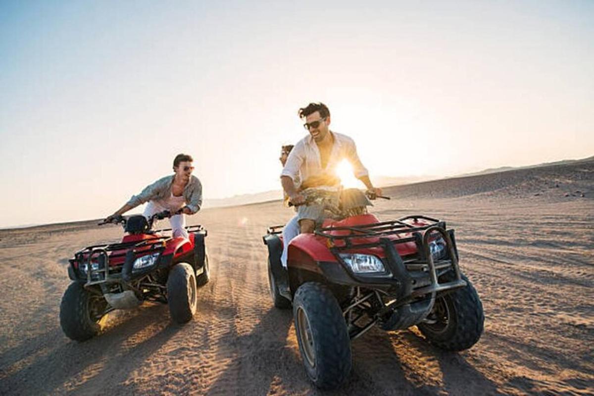 dua lelaki sedang menunggang atv di padang pasir