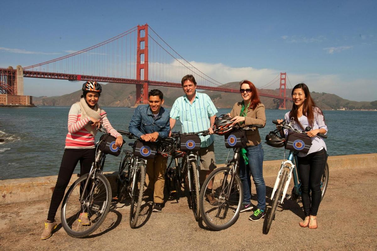 Un grupo de personas en bicicleta frente al puente Golden Gate.