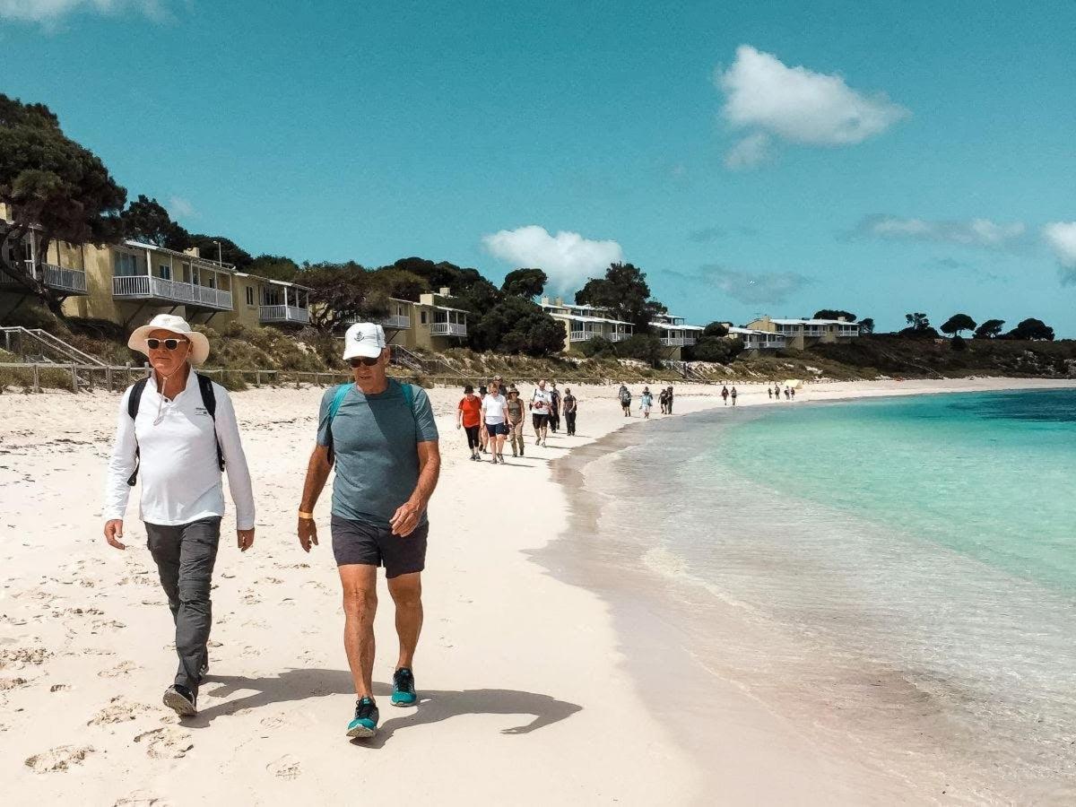 dois idosos caminhando na praia