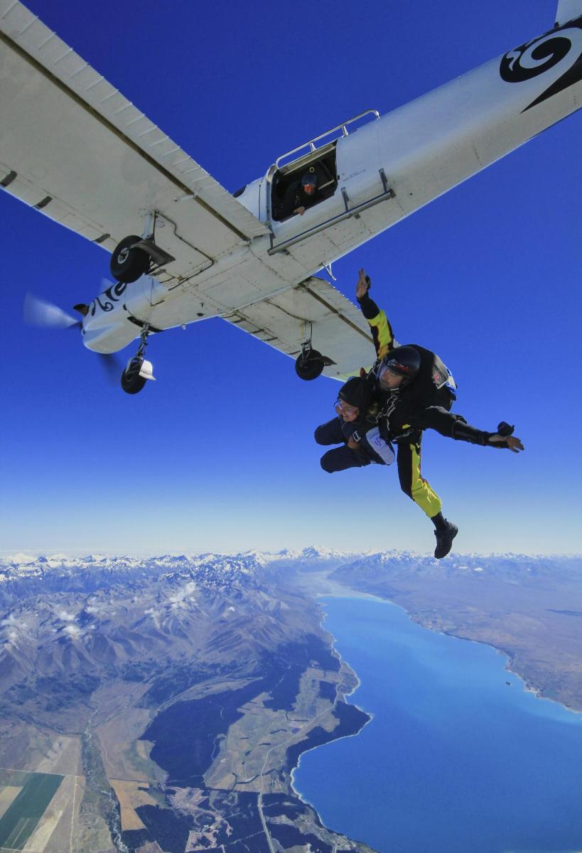 a person is hanging from the wing of an airplane