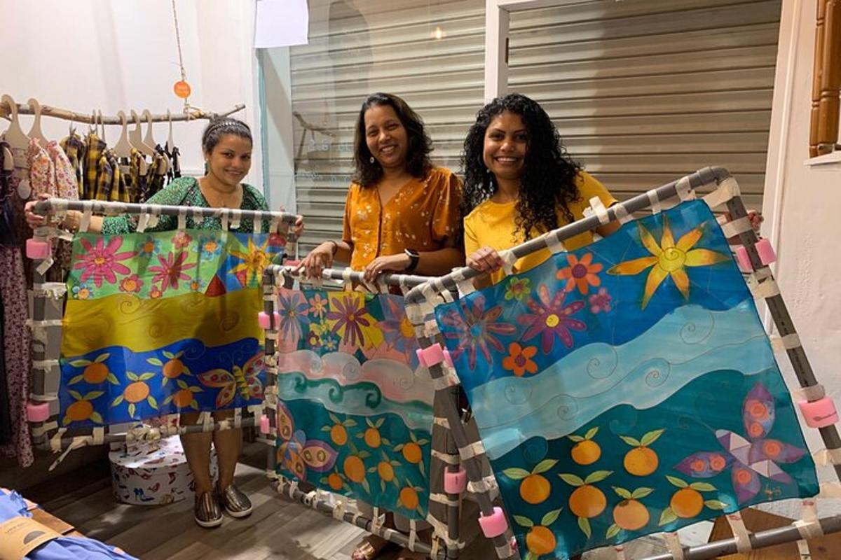 Tres mujeres sostienen un cuadro en una silla.