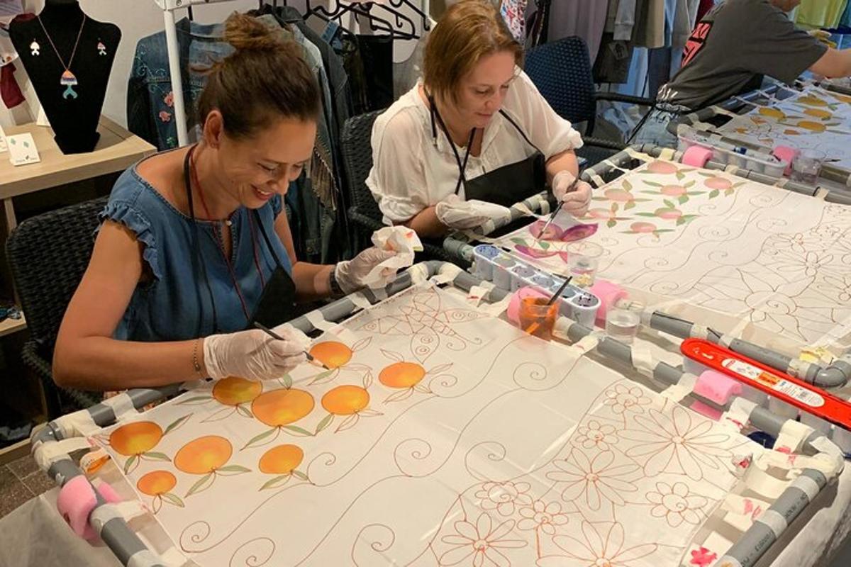 Dos mujeres están trabajando en una mesa con pintura encima.