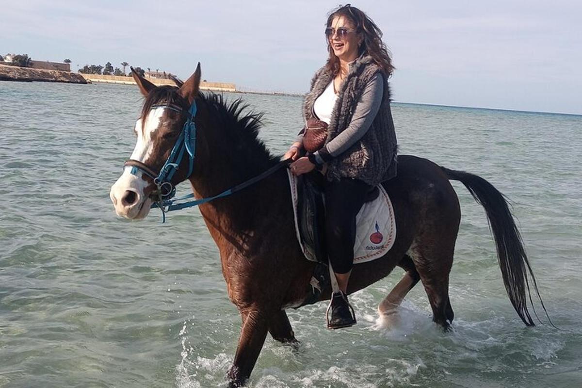 uma mulher cavalgando um cavalo na água