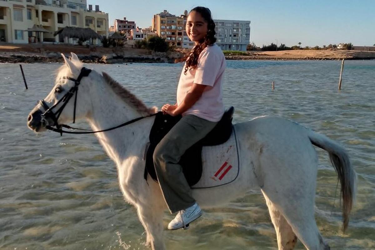una donna che cavalca un cavallo bianco nell'acqua