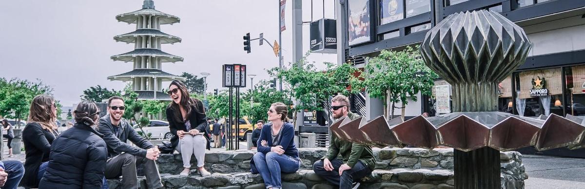 eine Gruppe von Menschen, die auf einer Mauer in der Nähe einer Straße sitzen
