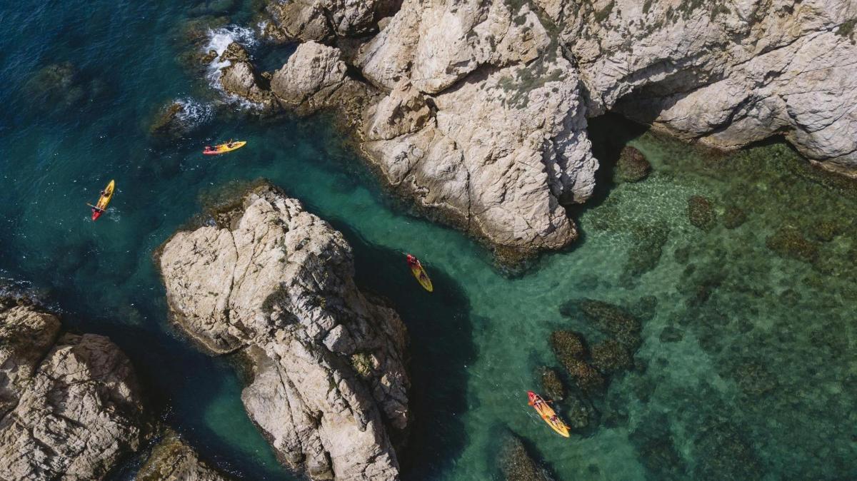 una vista aerea di persone che fanno kayak nell'acqua tra le rocce