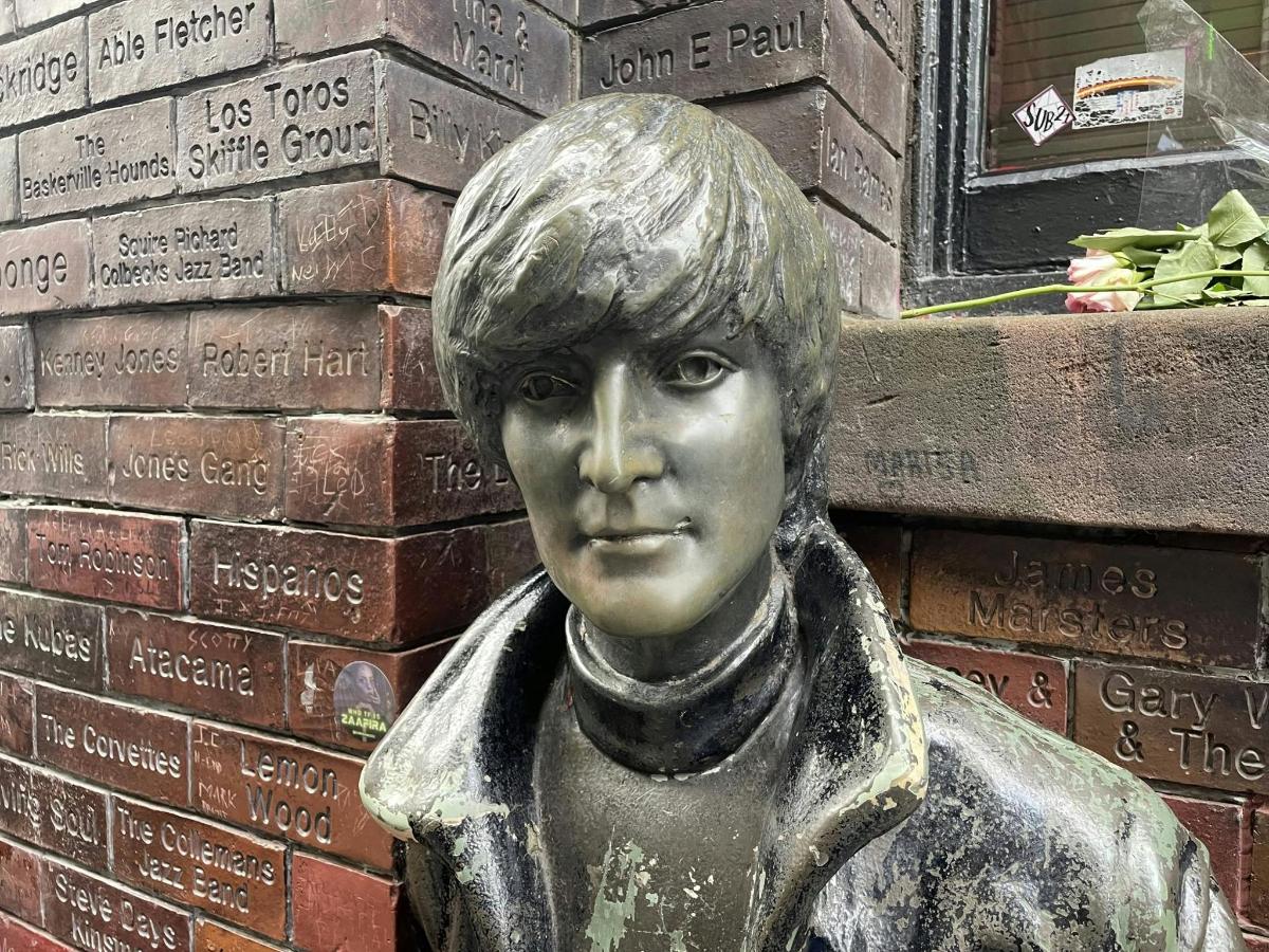 Una estatua de una niña frente a una pared de ladrillos.