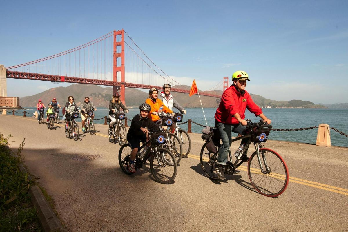 Un grupo de personas en bicicleta frente a un puente.