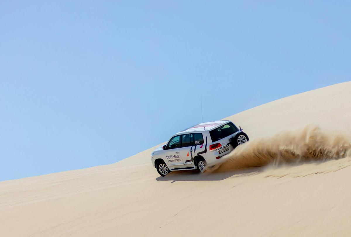 un camion bianco che percorre una duna di sabbia