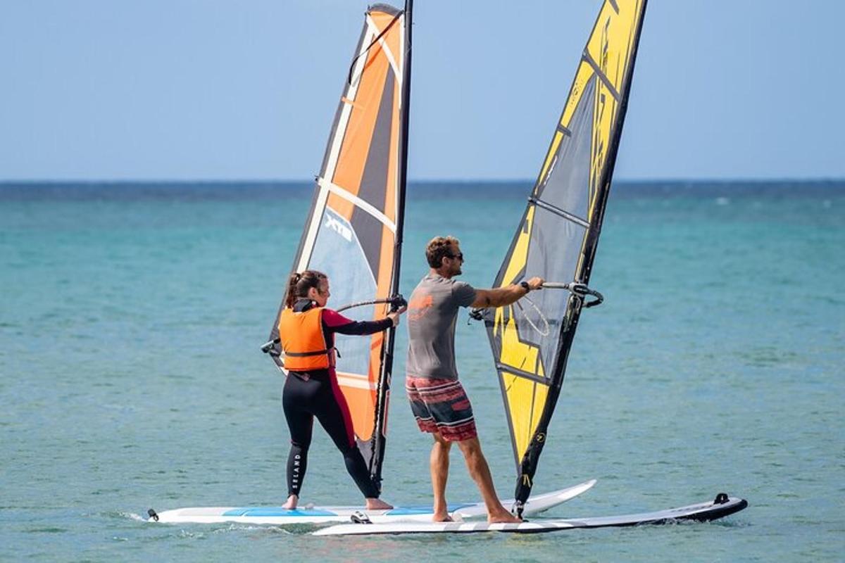 dalawang tao ang nakatayo sa mga surfboard na may windsurfing