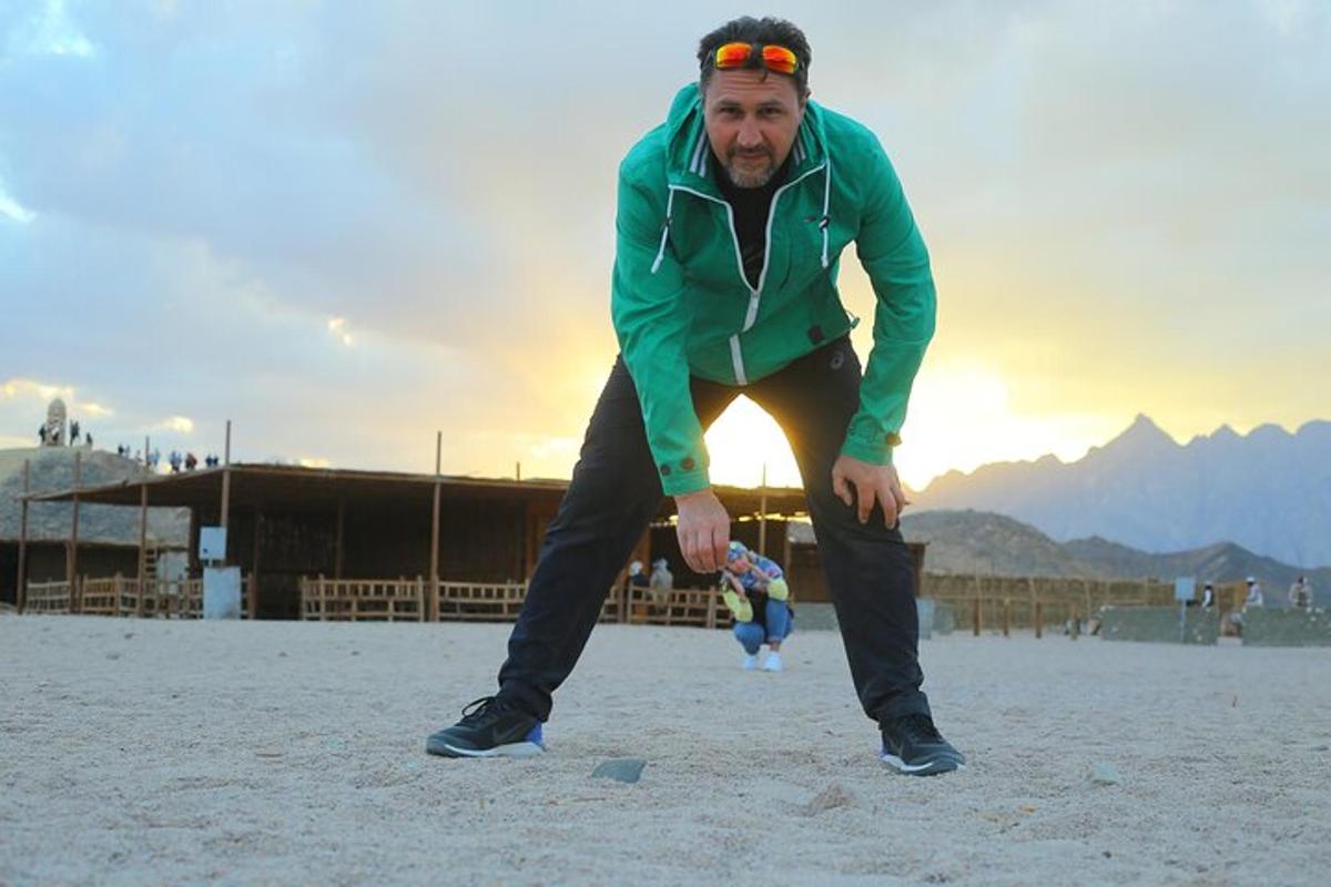 un uomo in piedi sulla spiaggia con una palla
