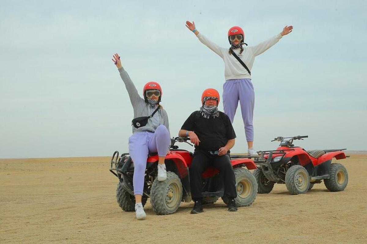 tre persone sono in piedi su quad nel deserto