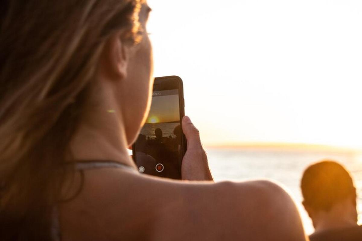 ženska, ki fotografira ocean s svojim mobilnim telefonom