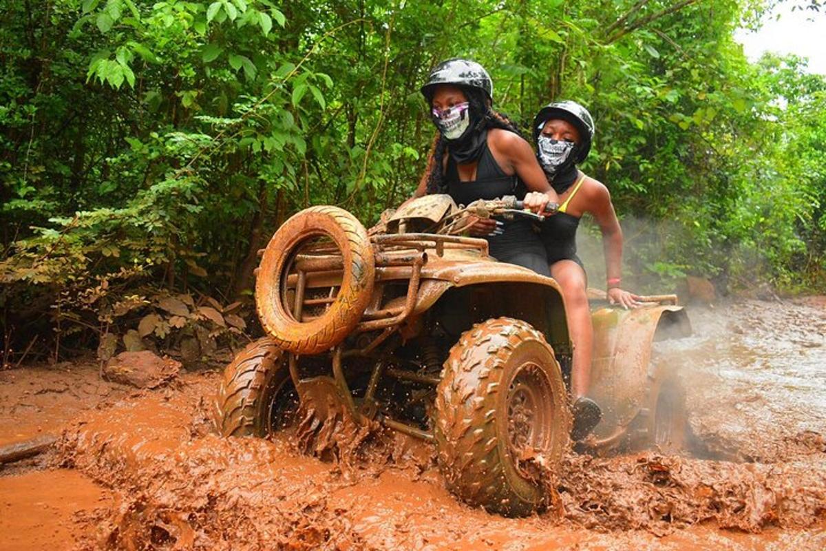 two people on an off road vehicle in the mud