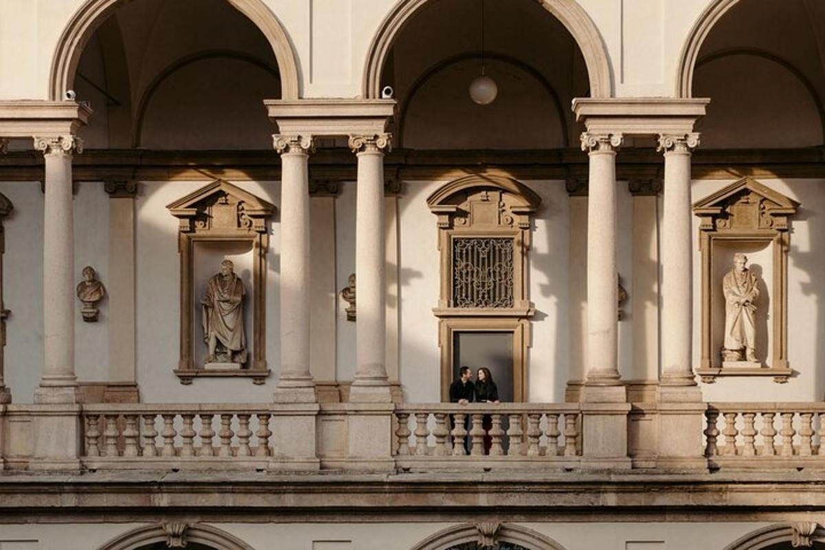 dues persones dretes al balcó d'un edifici amb estàtues