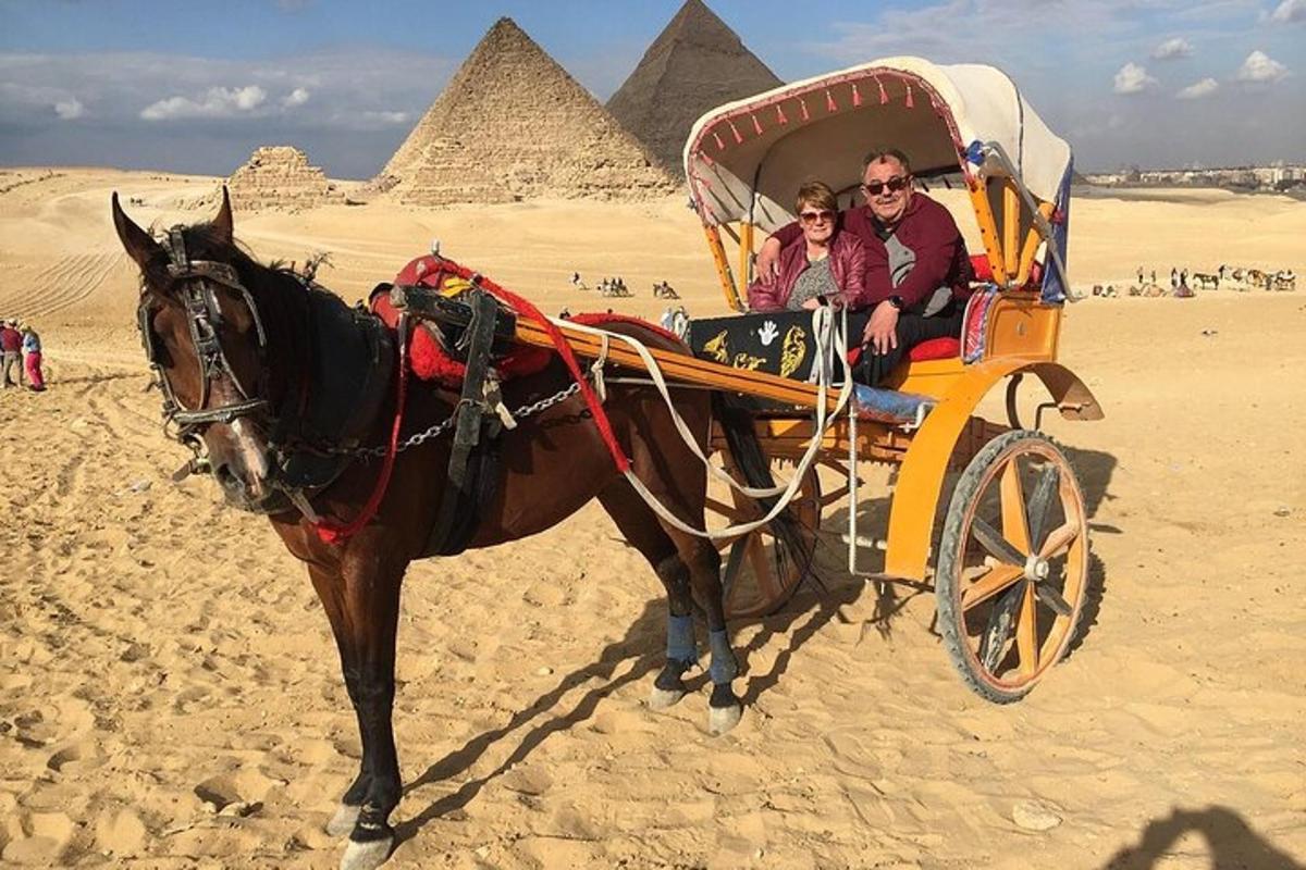 Dos personas viajando en un carruaje tirado por caballos frente a las pirámides
