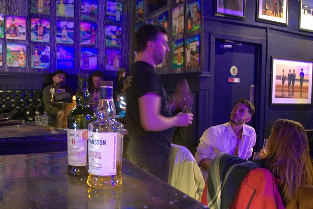 un bărbat care stă la un bar cu o sticlă de vin