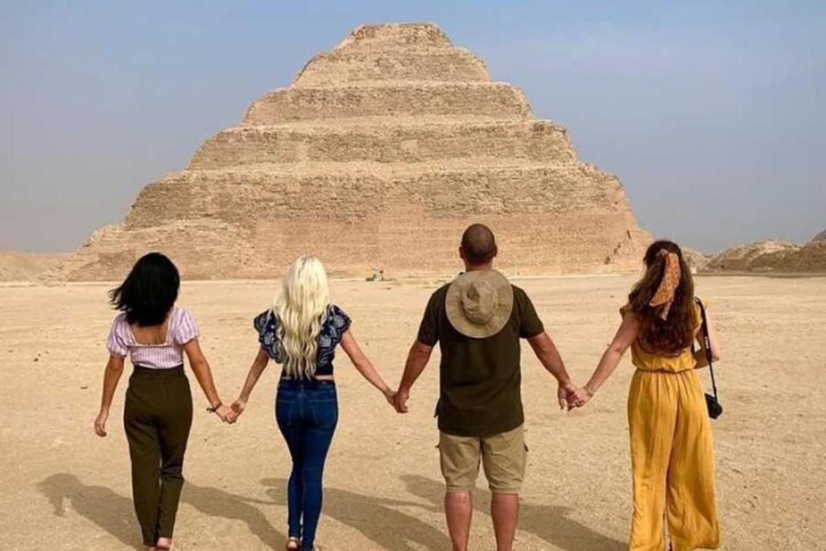 skupina lidí kráčejících před pyramidou